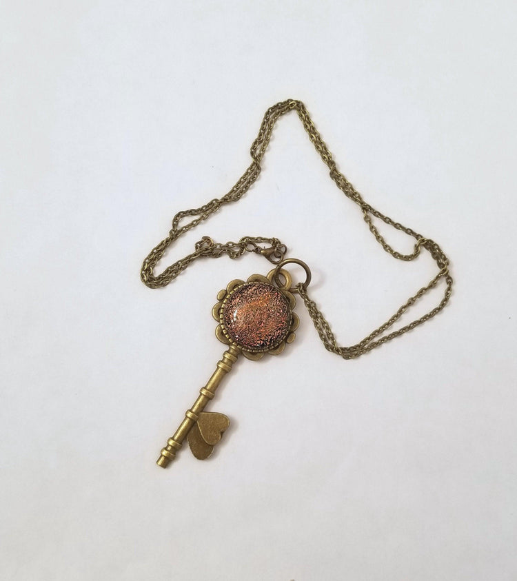 Antiqued Brass  Flowered Skeleton Key with Fused Glass Orange Dichroic cabochon on 24 inch brass plated chain. seeds glassworks. seedsglassworks